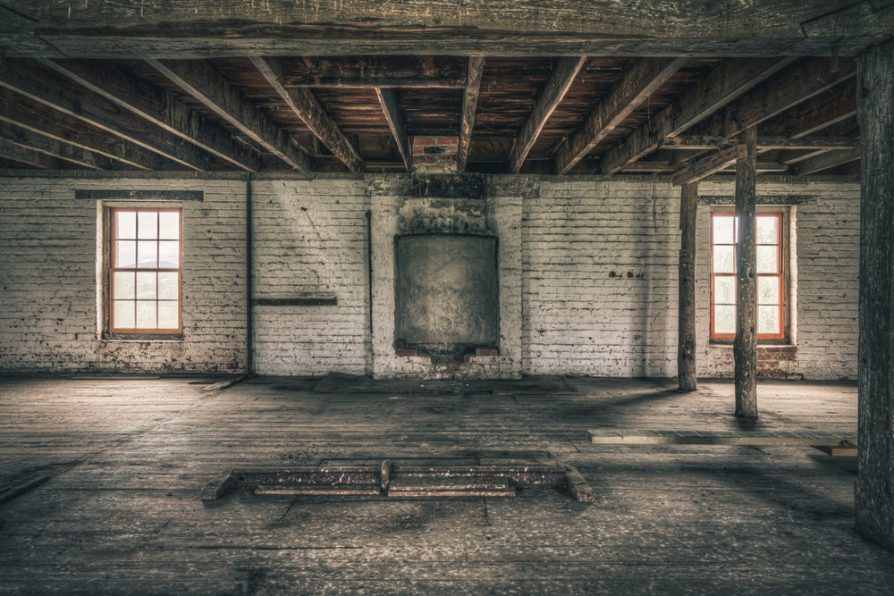 Upper room at Jembaicumbene mill, whitewashed brick walls and two sash windows over a bare timber floor.