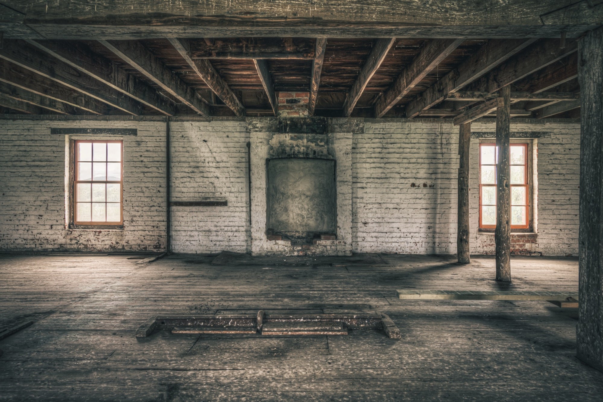 Upper room at Jembaicumbene mill, whitewashed brick walls and two sash windows over a bare timber floor.