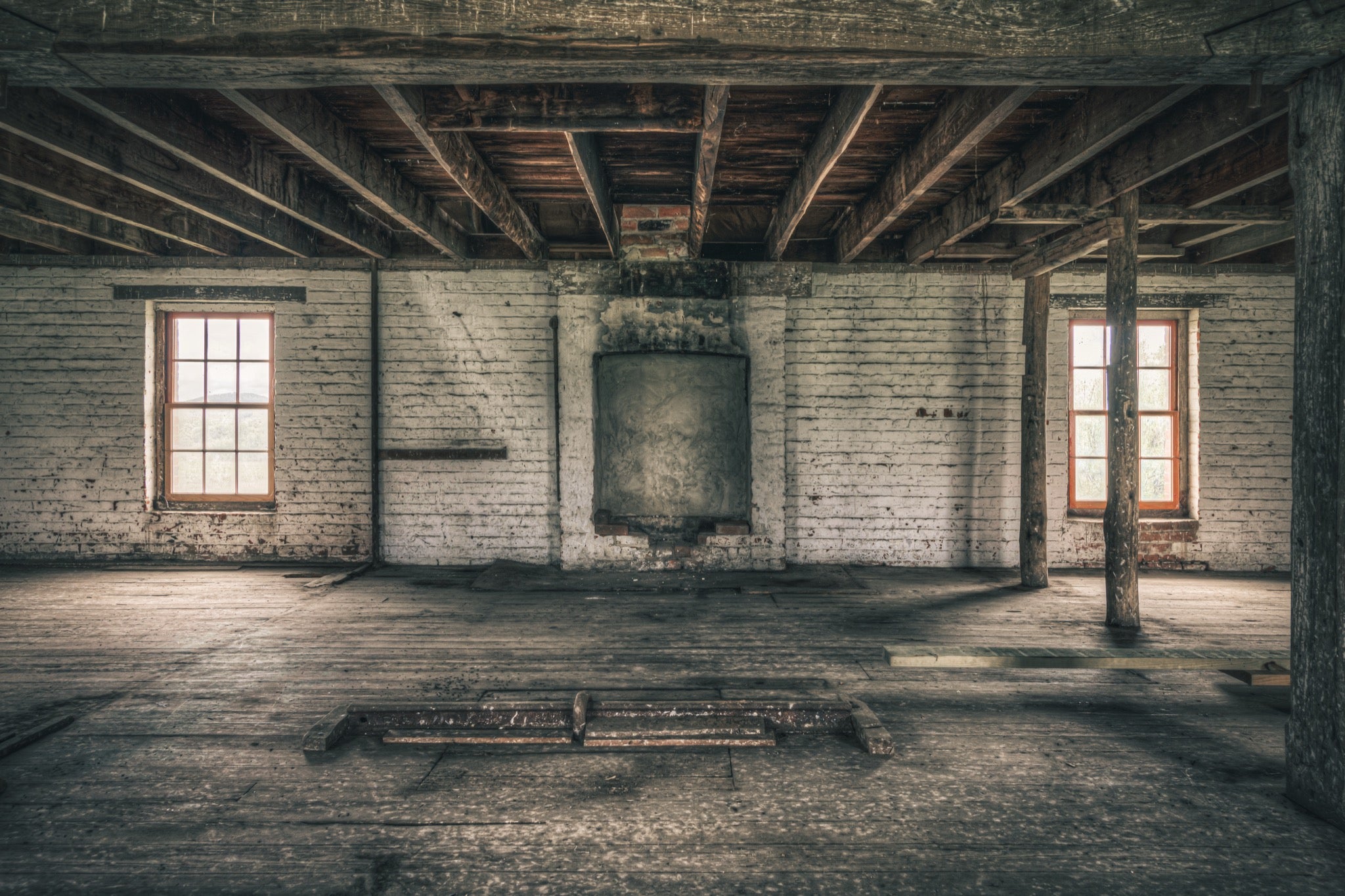 Upper room at Jembaicumbene mill, whitewashed brick walls and two sash windows over a bare timber floor.