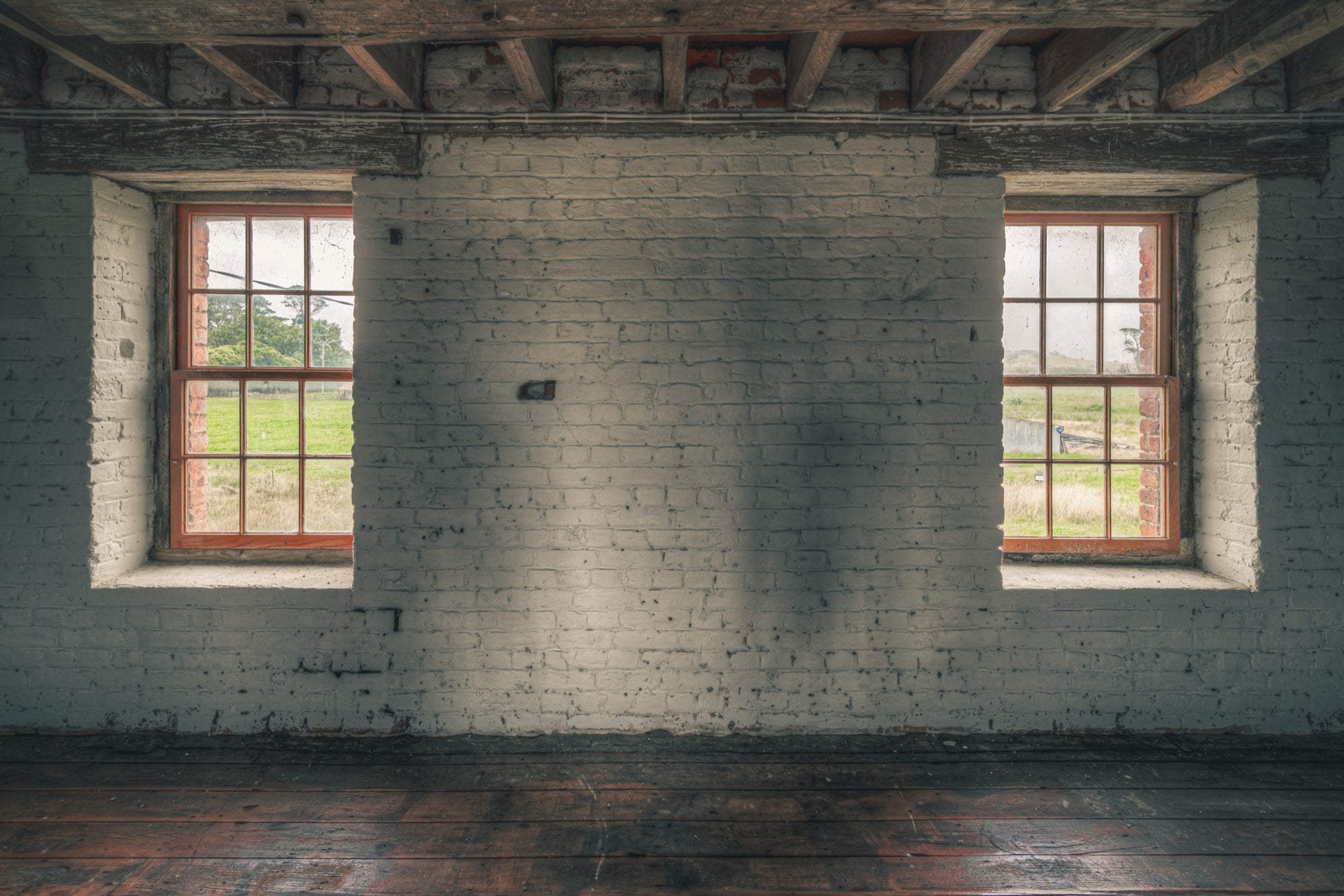 Twin timber sash windows at Jembaicumbene, whitewashed brick wall with exposed red brick reveals.