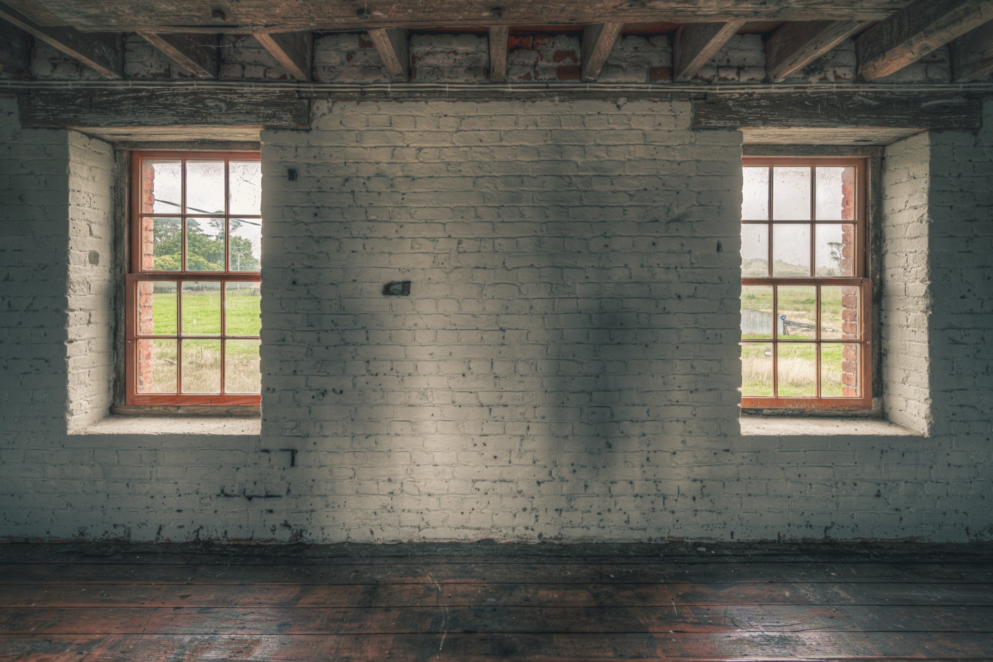 Twin timber sash windows at Jembaicumbene, whitewashed brick wall with exposed red brick reveals.