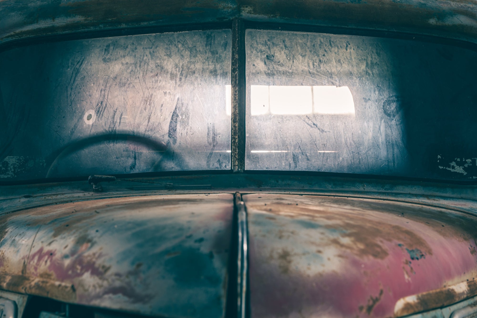 Split windscreen and bonnet of an old vehicle at Jembaicumbene, scratched glass and rusted paint.