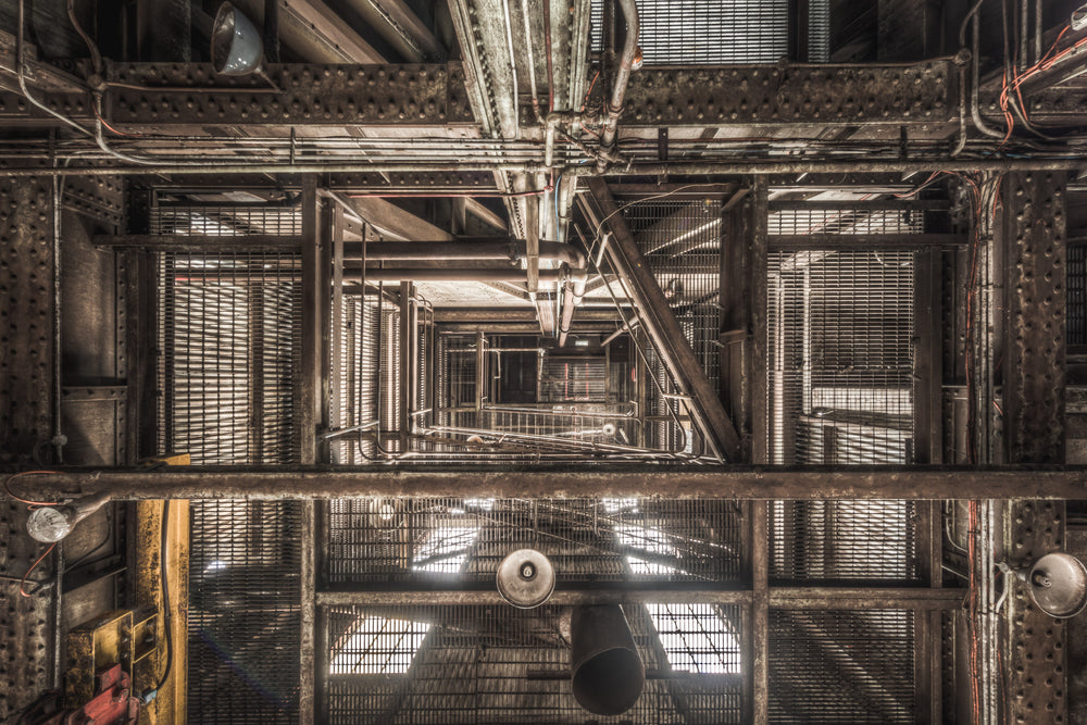 Ascent at Morwell Power Station, steel grating and riveted iron columns stack upward through multiple levels, viewed.