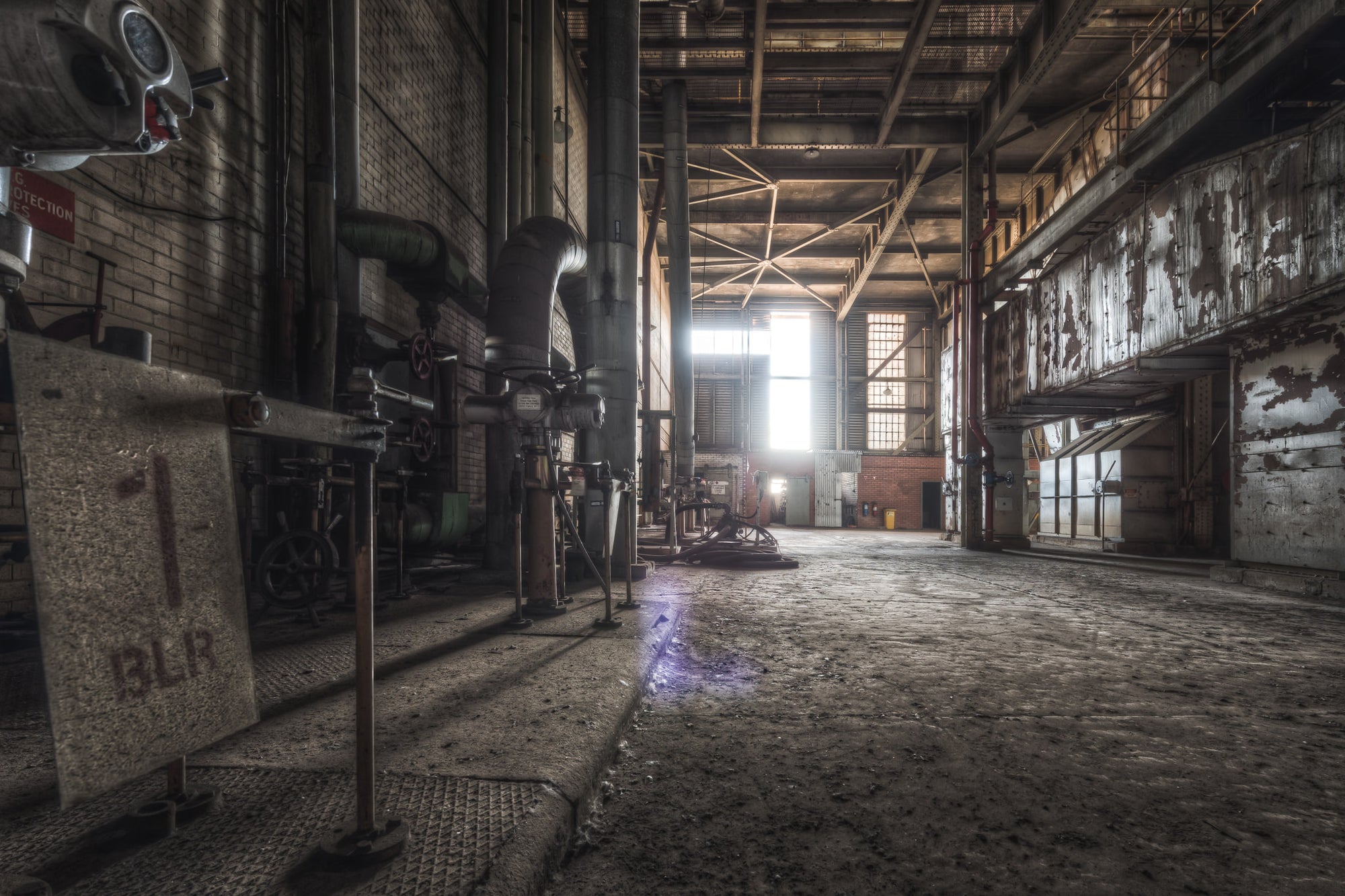 Boiler House 2 at Morwell Power Station, steel pipework and heavy valve assemblies line the left wall, bolted to brown brick.
