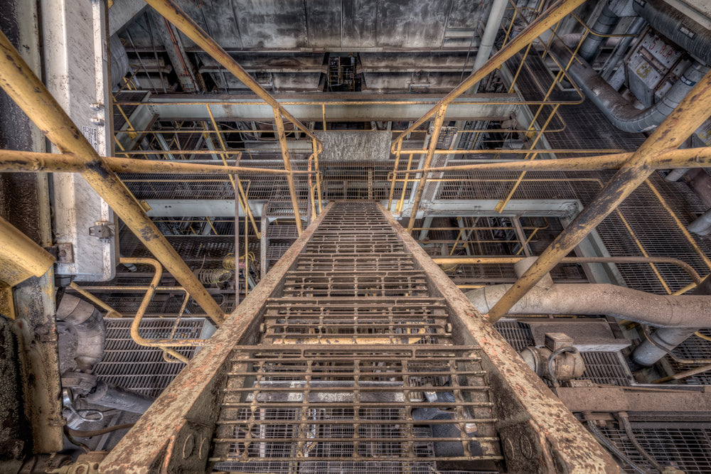 Descent at Morwell Power Station, a steel grate staircase climbs steeply between levels inside the boiler house.
