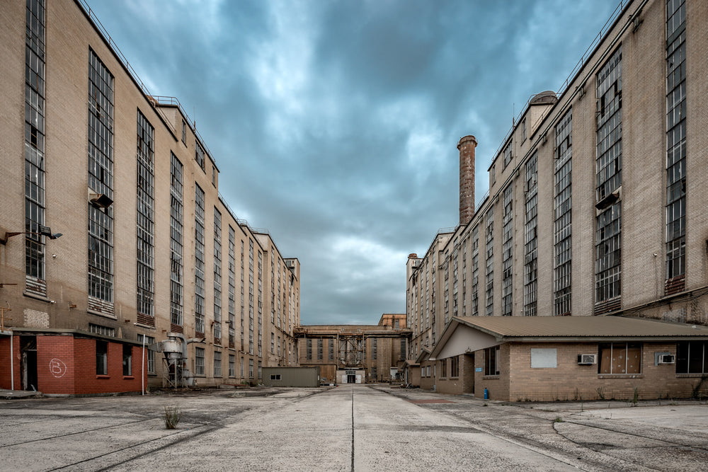 Divider at Morwell Power Station, two multi-storey brick buildings stand parallel, forming a wide concrete corridor.