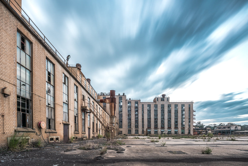 Launder Yard at Morwell Power Station, cream brick buildings rise several storeys high across a cracked concrete yard.