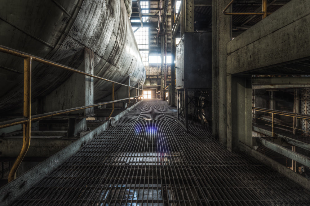 Steam Vessel at Morwell Power Station, a steel grating walkway runs between a massive cylindrical vessel and a concrete.