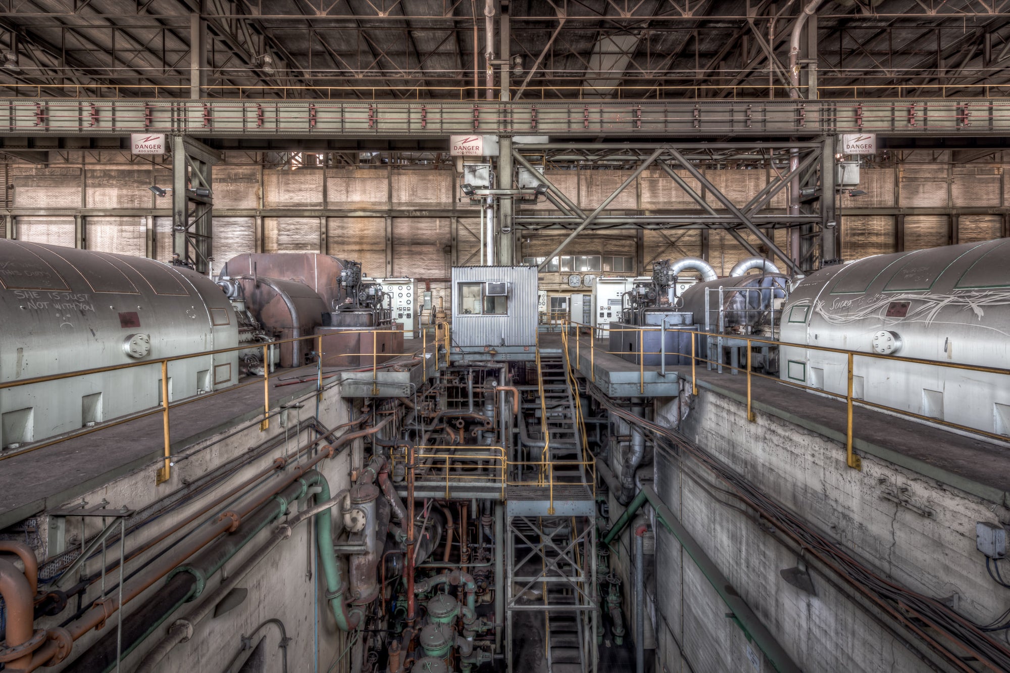Turbine Floor at Morwell Power Station, four turbo-alternator units sit in two rows, their cylindrical steel casings grey.