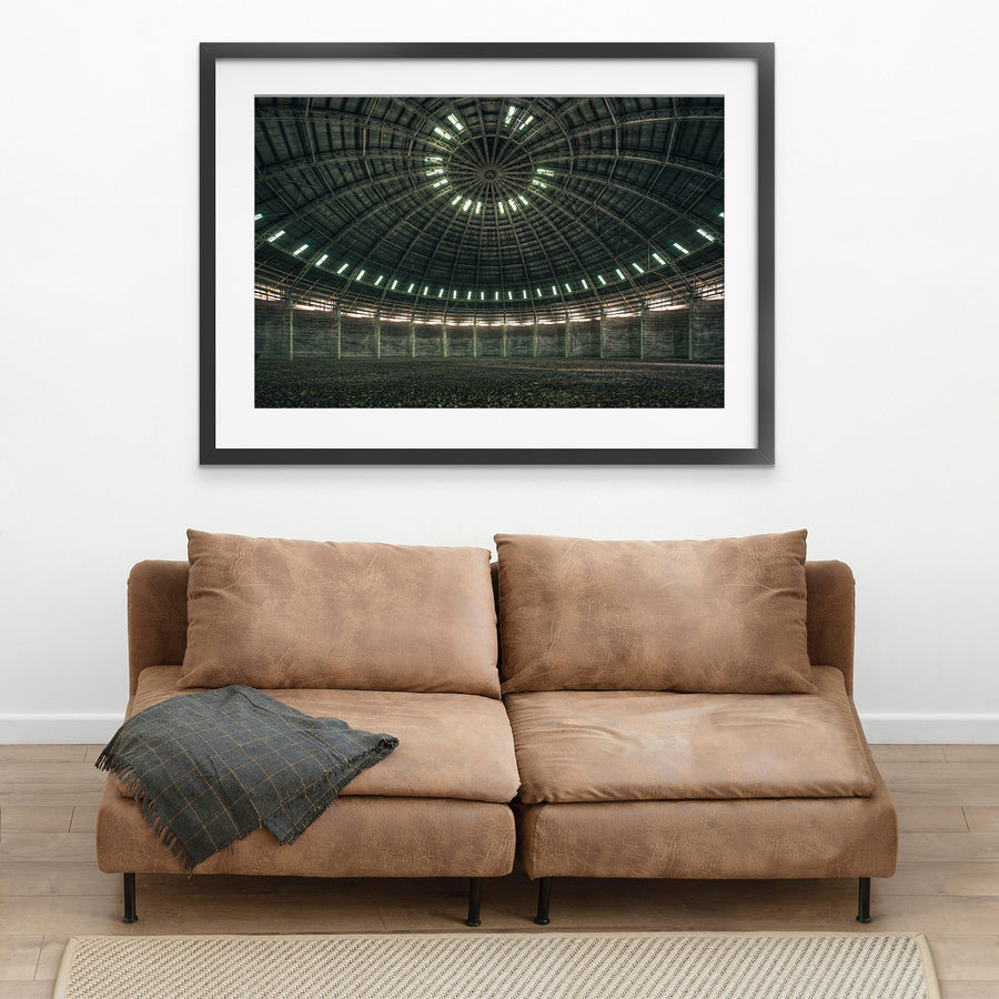 View looking up at the steel-framed dome interior of the grain silo at Mount Russell, with concentric skylight openings and a gravel-covered floor below.