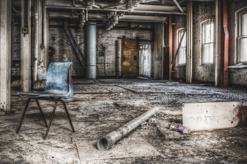 Bagging Room at Mungo Scott Flour Mill, a blue moulded-plastic chair sits alone on a concrete floor thick with grit and dust.
