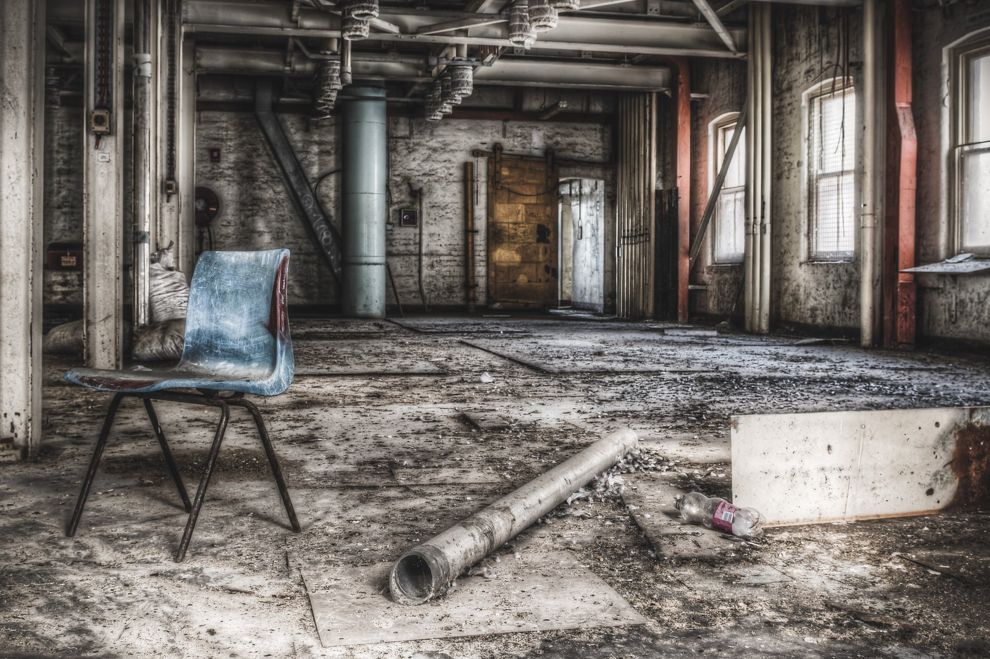 Bagging Room at Mungo Scott Flour Mill, a blue moulded-plastic chair sits alone on a concrete floor thick with grit and dust.
