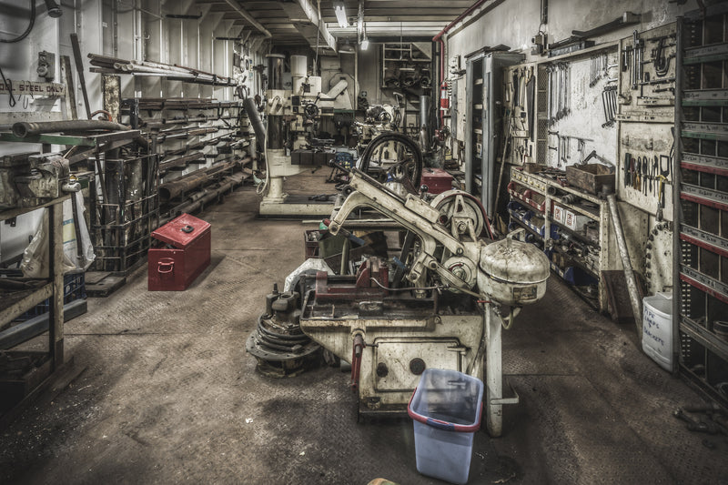 Machine Shop at MV Cape Don, a horizontal bandsaw sits centre-floor, its blade guard and drive wheel coated in pale grime.
