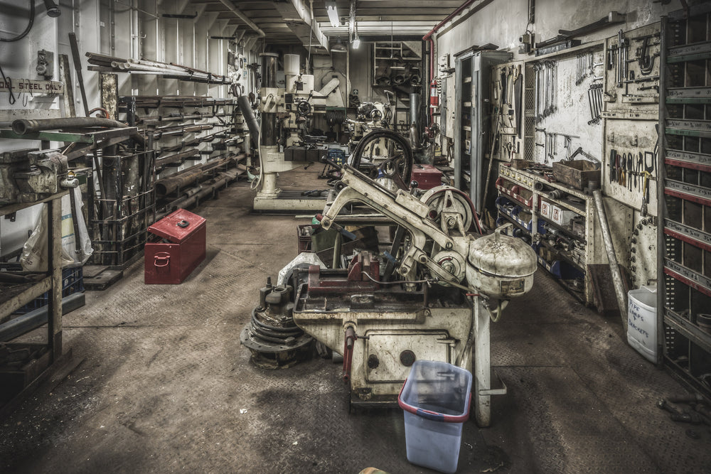 Machine Shop at MV Cape Don, a horizontal bandsaw sits centre-floor, its blade guard and drive wheel coated in pale grime.