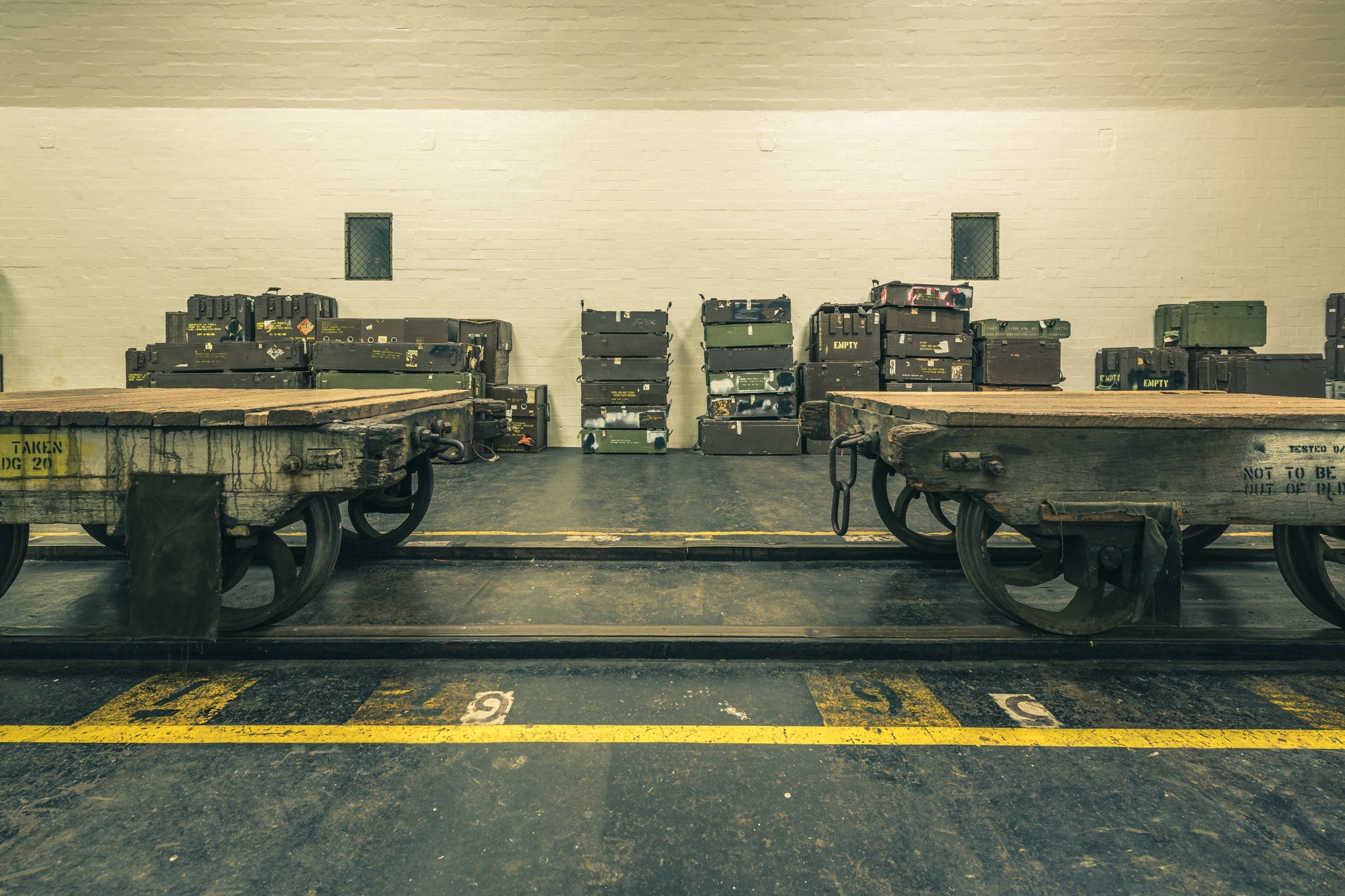 Carts at Newington Armory, two heavy timber flatbed trolleys sit side by side on a dark concrete floor.