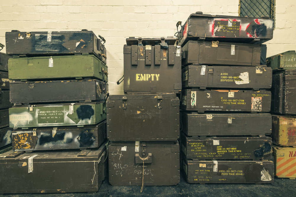Crates at Newington Armory, military munitions crates stacked three columns high against a whitewashed brick wall.