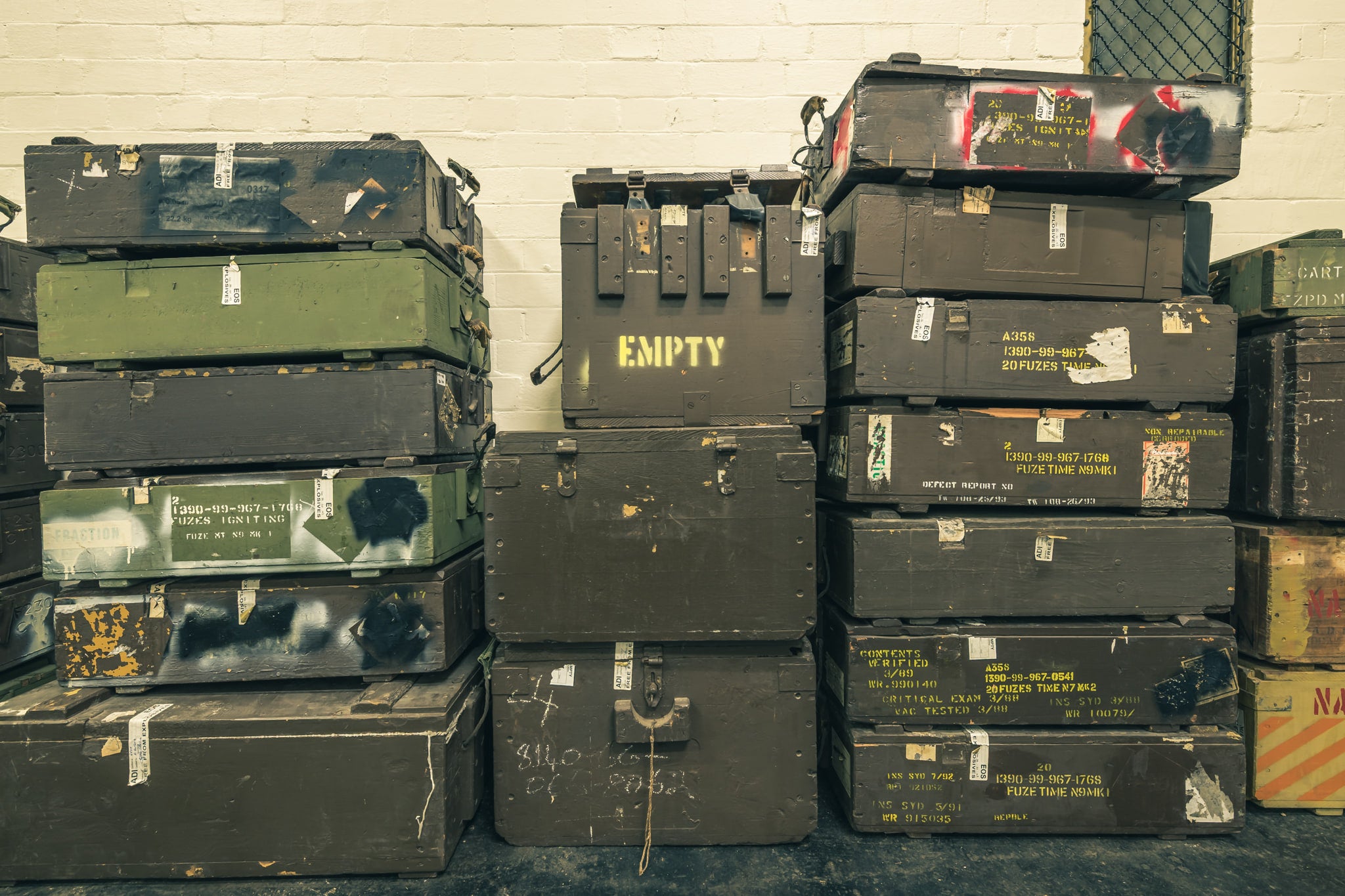 Crates at Newington Armory, military munitions crates stacked three columns high against a whitewashed brick wall.