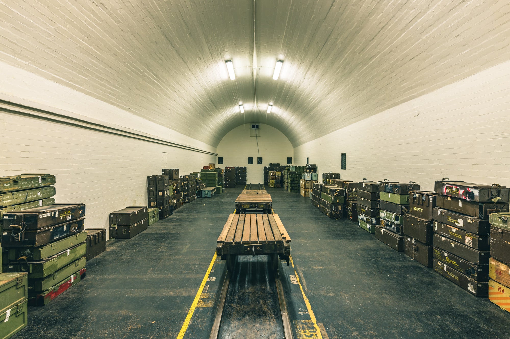 Magazine Interior at Newington Armory, a barrel-vaulted ceiling of whitewashed brick curves over rows of military ordnance.