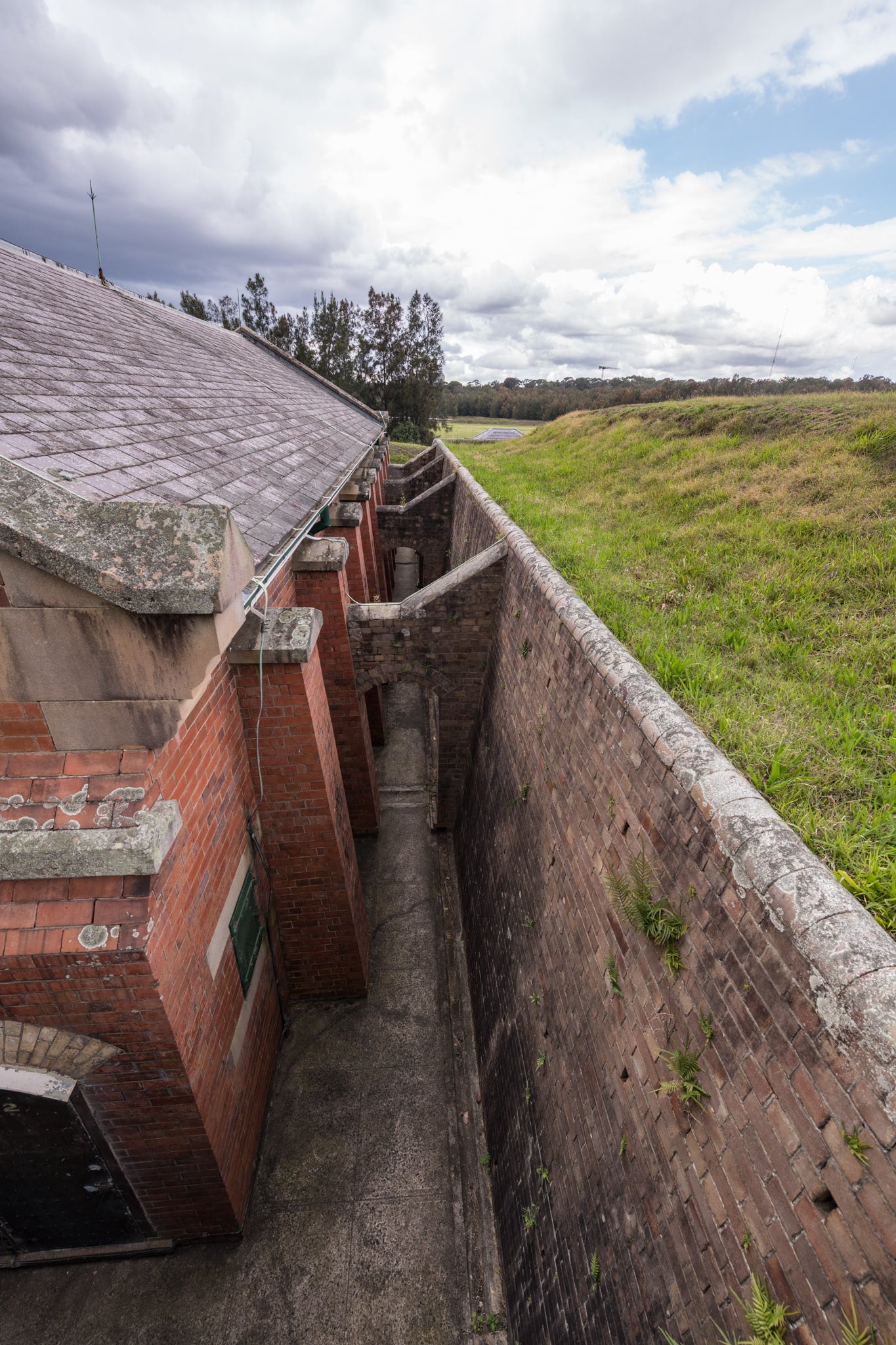 Magazine Looking Down at Newington Armory, a narrow passage runs between the red brick facade of a munitions magazine.
