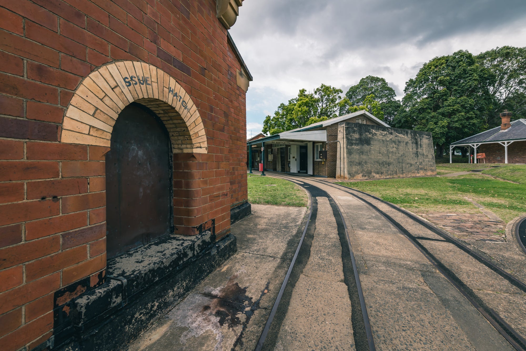 Rails at Newington Armory, narrow-gauge rails curve across a concrete apron, running past the issue hatch of a red brick.
