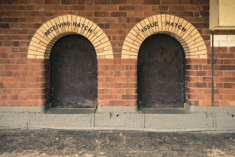 Recieving Issue at Newington Armory, two arched hatches sit side by side in a red brick wall.