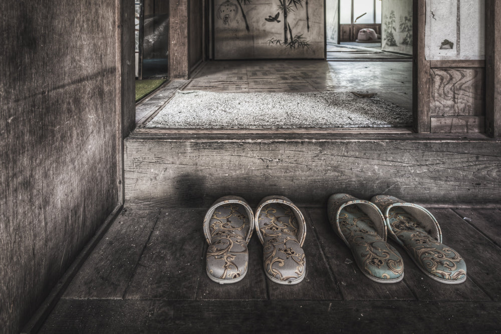 Genkan at Nichitsu Mining Village, two pairs of slippers sit on the worn timber floor of a genkan, their floral fabric.