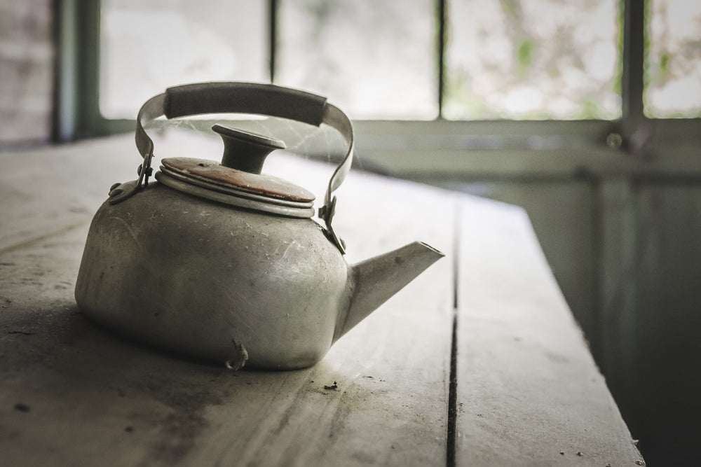 Kettle at Nichitsu Mining Village, an aluminium kettle sits on a timber bench beside a window.