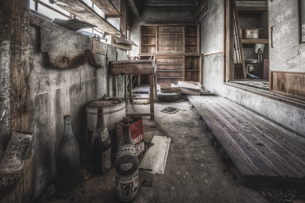 Laundry at Nichitsu Mining Village, glass bottles and a rusted fuel tin sit against a concrete wall, their labels faded.