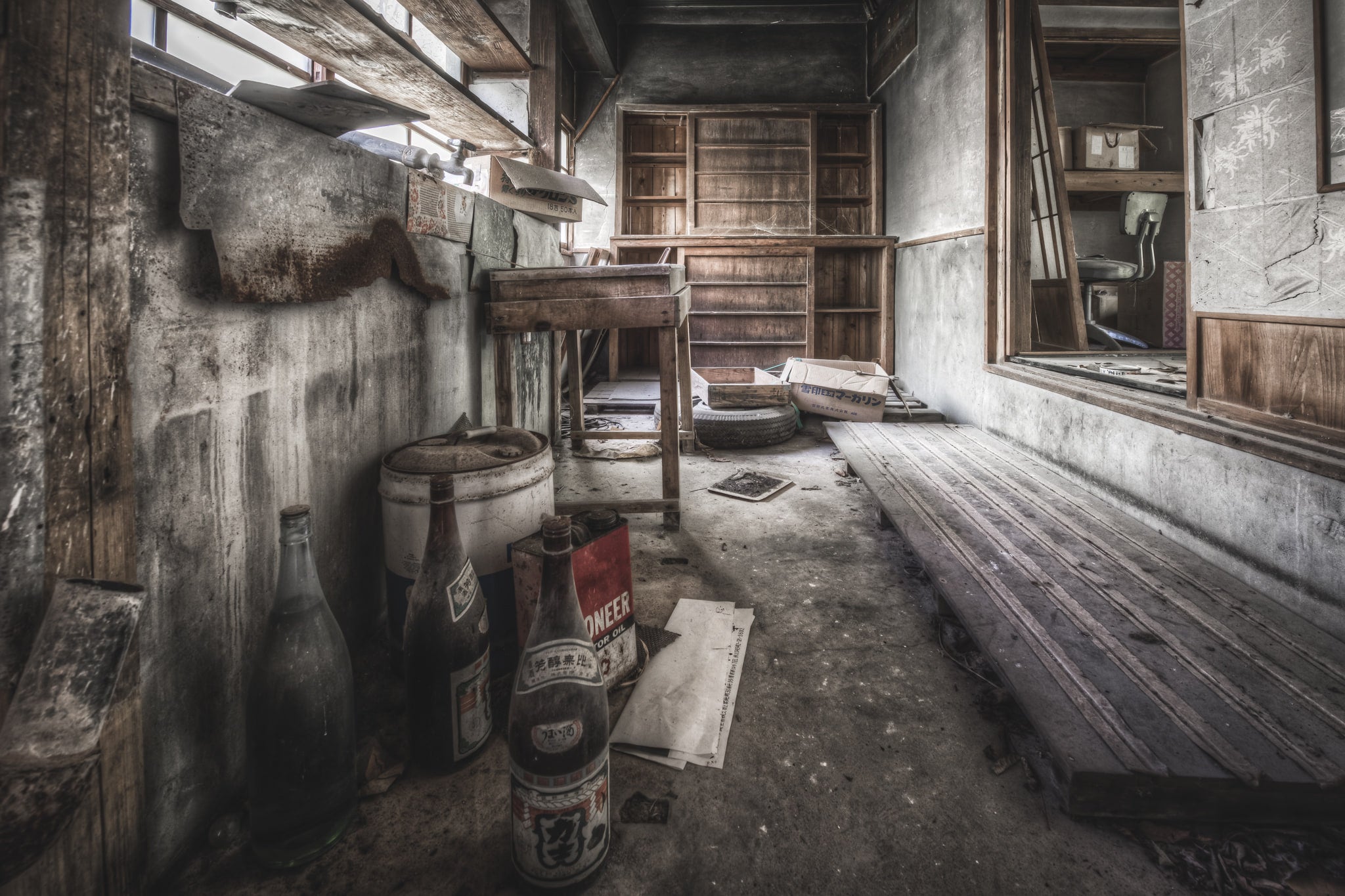 Laundry at Nichitsu Mining Village, glass bottles and a rusted fuel tin sit against a concrete wall, their labels faded.