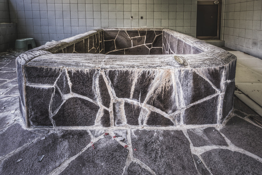 Public Bath at Nichitsu Mining Village, a hexagonal stone bath sits dry and empty in a tiled room.