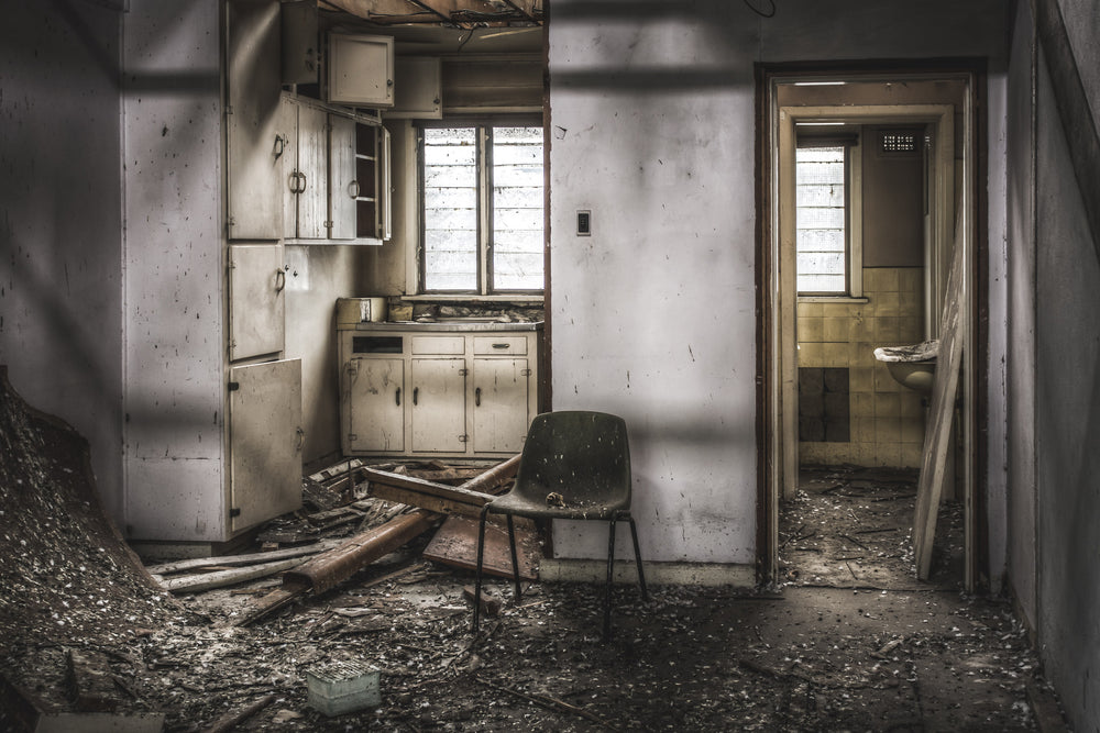 Living Quarters at O-I Glass, a moulded fibreglass chair sits in the centre of a wrecked kitchenette.