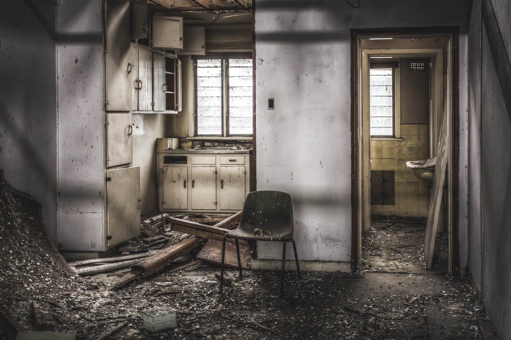 Living Quarters at O-I Glass, a moulded fibreglass chair sits in the centre of a wrecked kitchenette.