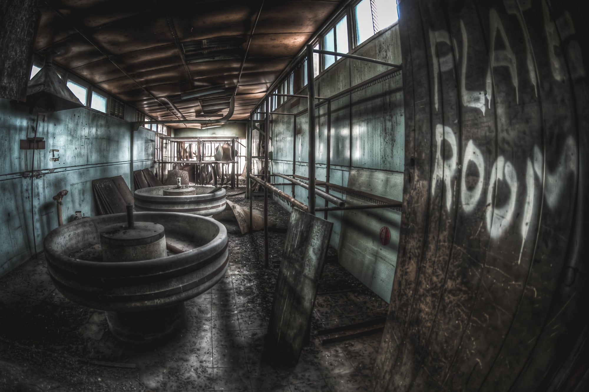 Plate Room at O-I Glass, large circular vats sit low on a wet concrete floor.