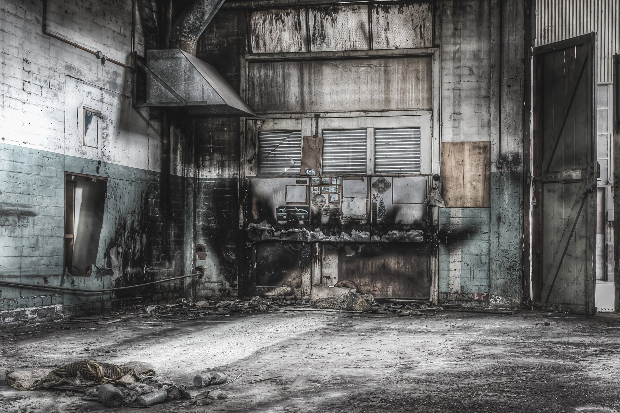 Welding Bay at O-I Glass, a high-ceilinged industrial bay with pale blue blockwork walls stained dark where heat and grease.