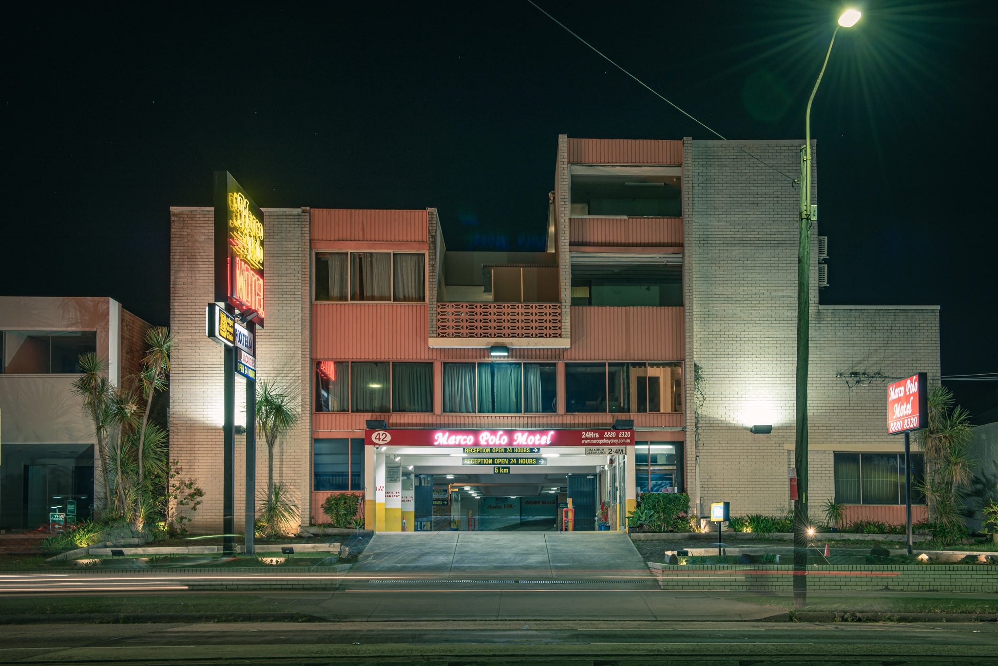 Marco Polo Motel at Parramatta Road, three storeys of grey brick columns frame open balconies with decorative breezeblock.