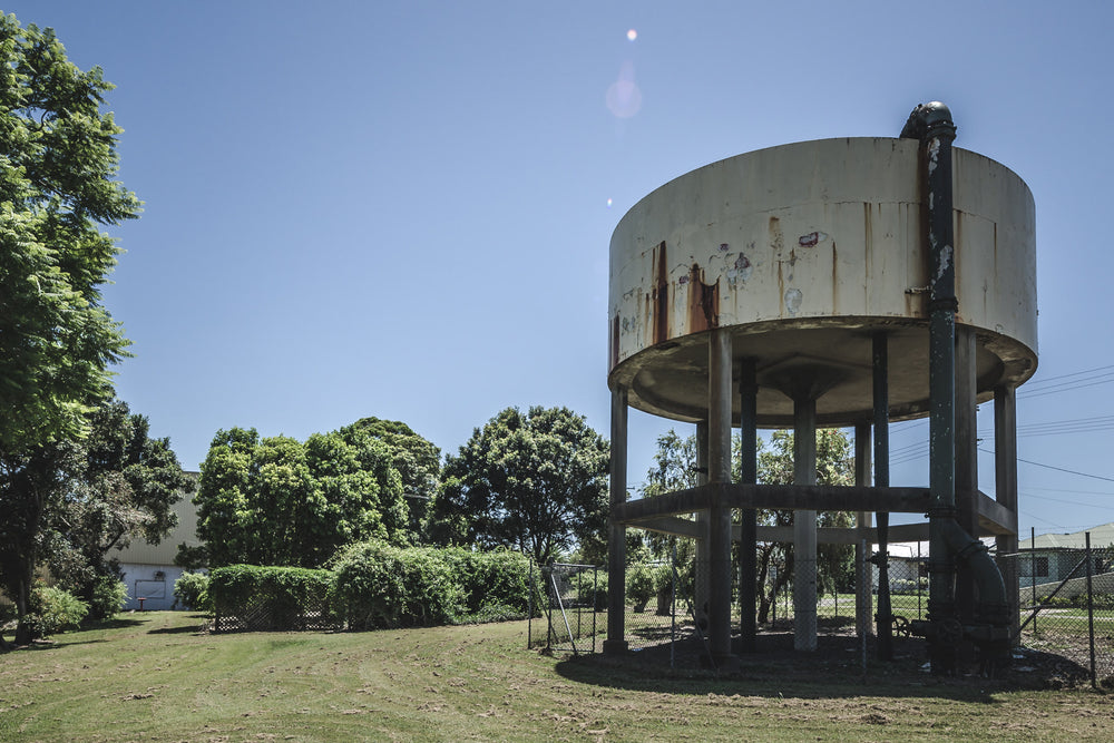 Front Lawn at Peters Ice Cream Factory, a cylindrical steel water tank sits raised on six legs above a mowed front lawn.