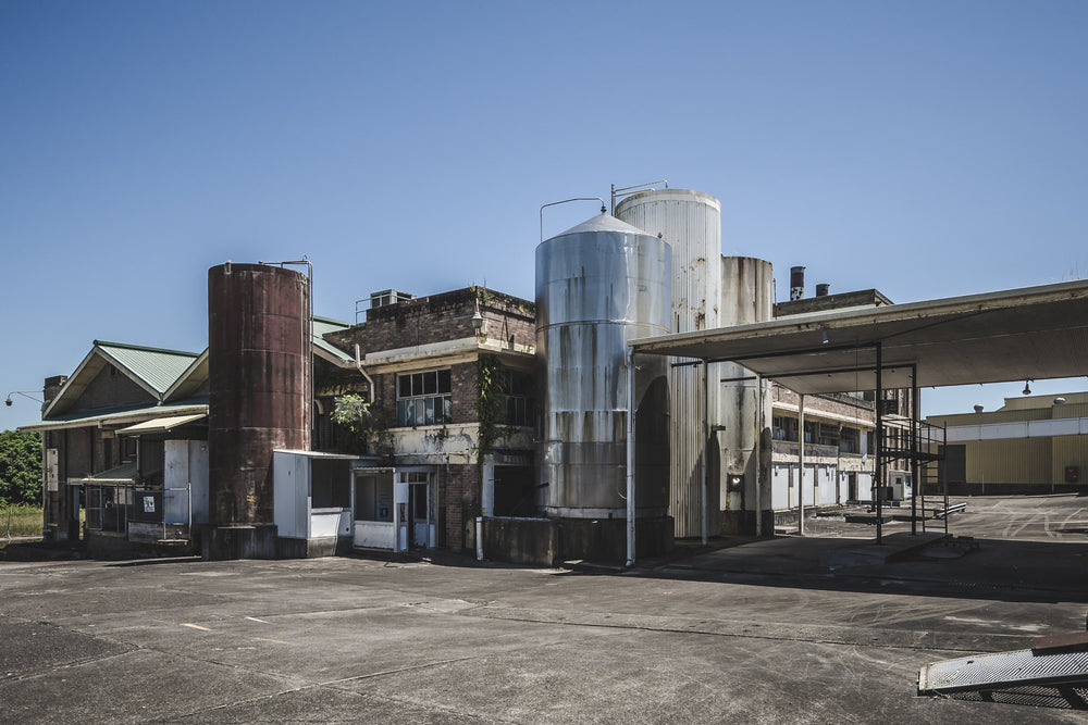 North Eastern Corner at Peters Ice Cream Factory, stainless steel silos and a rusted cylindrical tank rise above the concrete yard at the north-eastern corner of the Peters Ice Cream Factory in Warwick Farm.