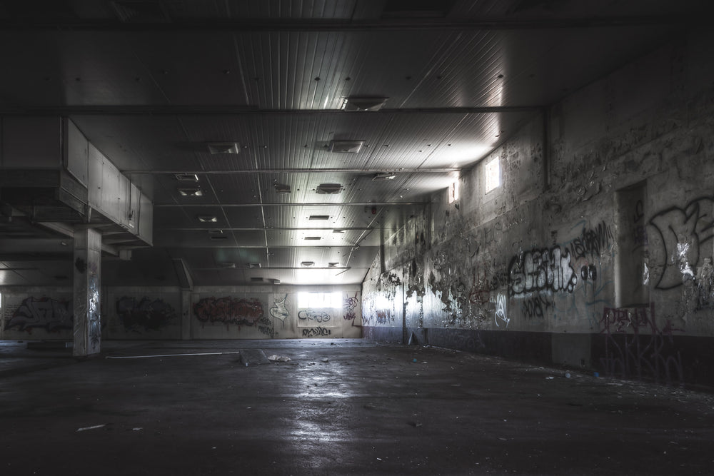 Production Floor at Peters Ice Cream Factory, a wide concrete floor stretches into shadow beneath a corrugated metal ceiling.