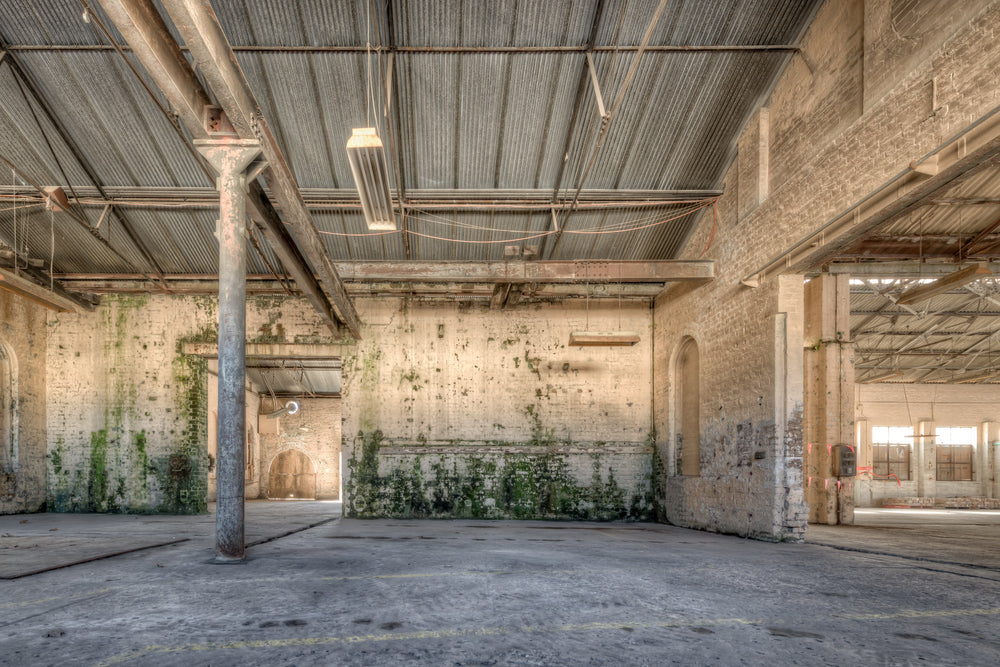Blacksmith Workshop at Portland Cement Works, a steel column rises from the concrete floor to a corrugated iron roof.