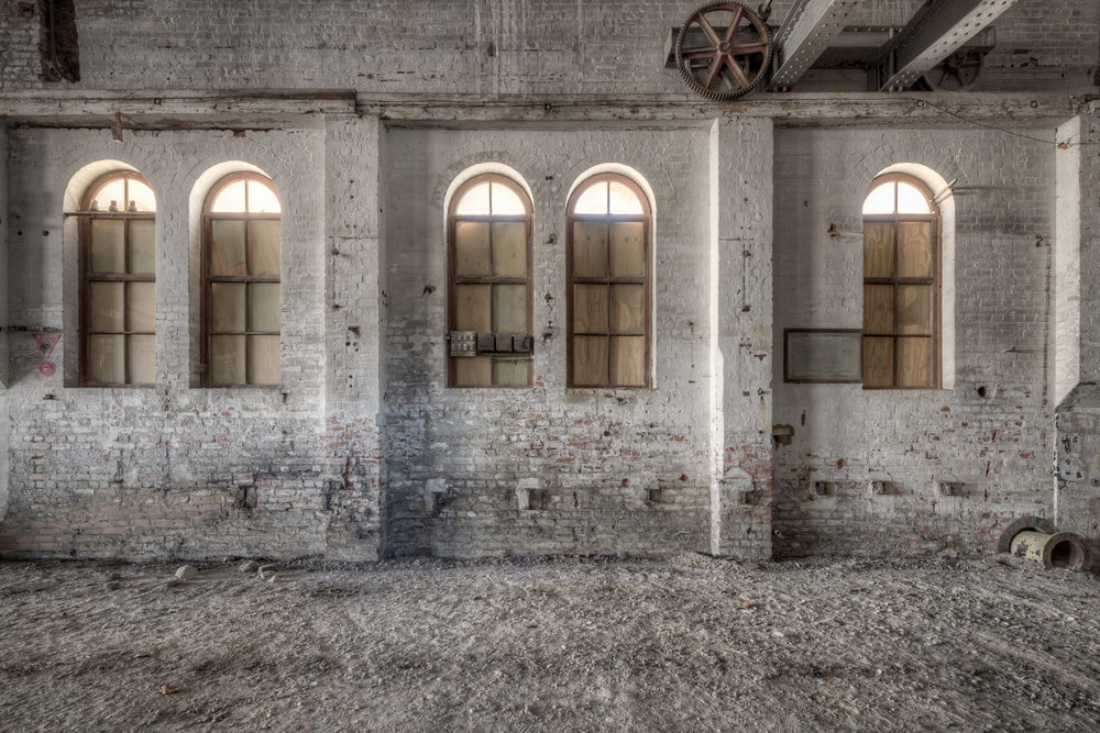 Boarded Arches at Portland Cement Works, three arched windows line the interior brick wall, their lower panes boarded.