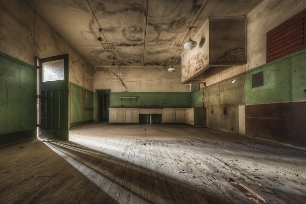 Kitchen at Portland Cement Works, low afternoon light cuts through a doorway and stretches across bare timber floorboards.