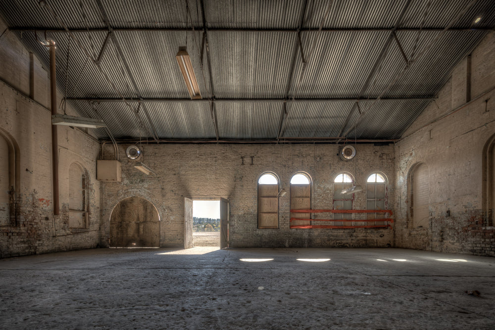 Opening at Portland Cement Works, pale brick walls rise to a corrugated iron roof inside one of the Portland Cement Works.