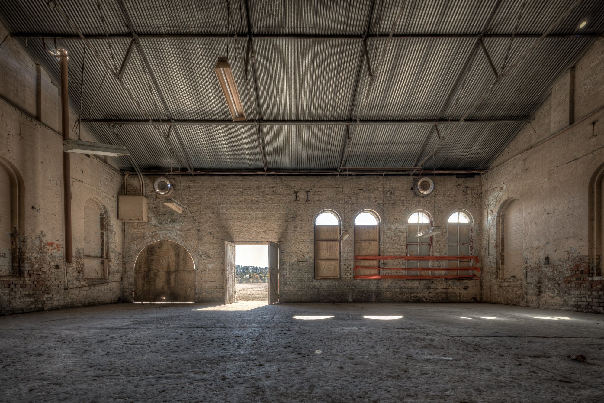 Opening at Portland Cement Works, pale brick walls rise to a corrugated iron roof inside one of the Portland Cement Works.