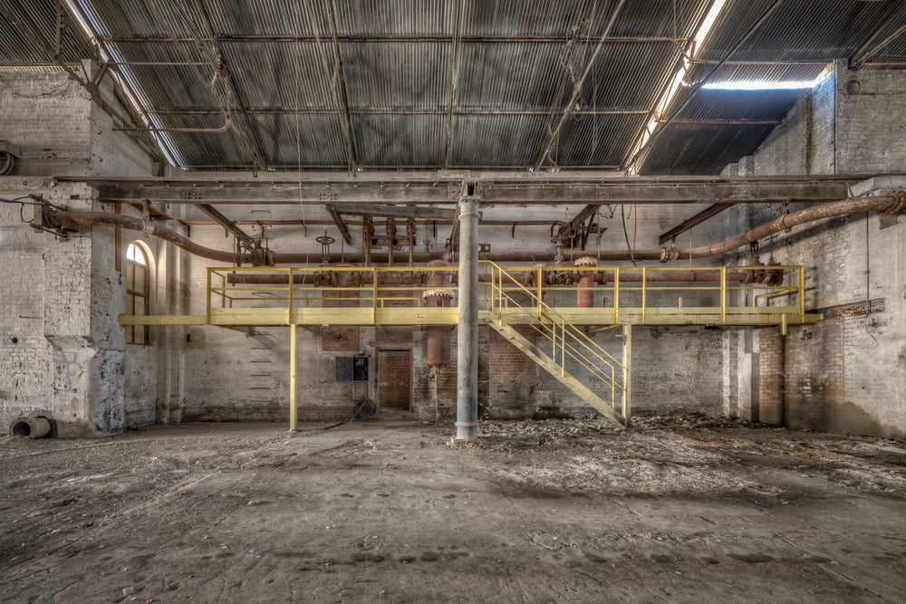 Pipework at Portland Cement Works, a yellow steel mezzanine spans the width of the building, its walkway and staircase.