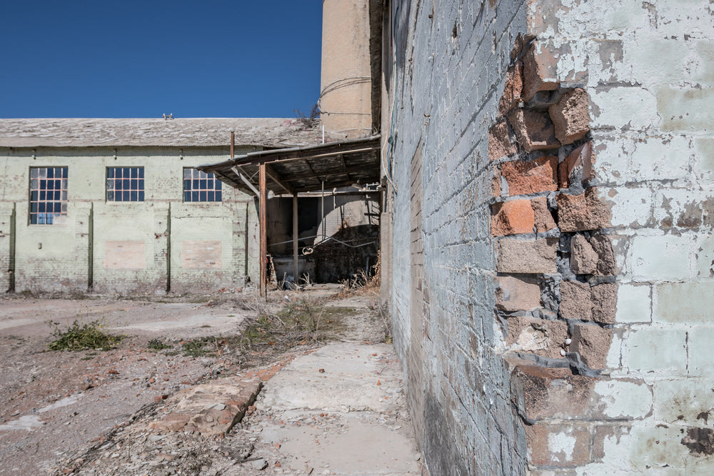 Power House Corner at Portland Cement Works, pale green paint peels from blockwork walls where the render has fallen away.