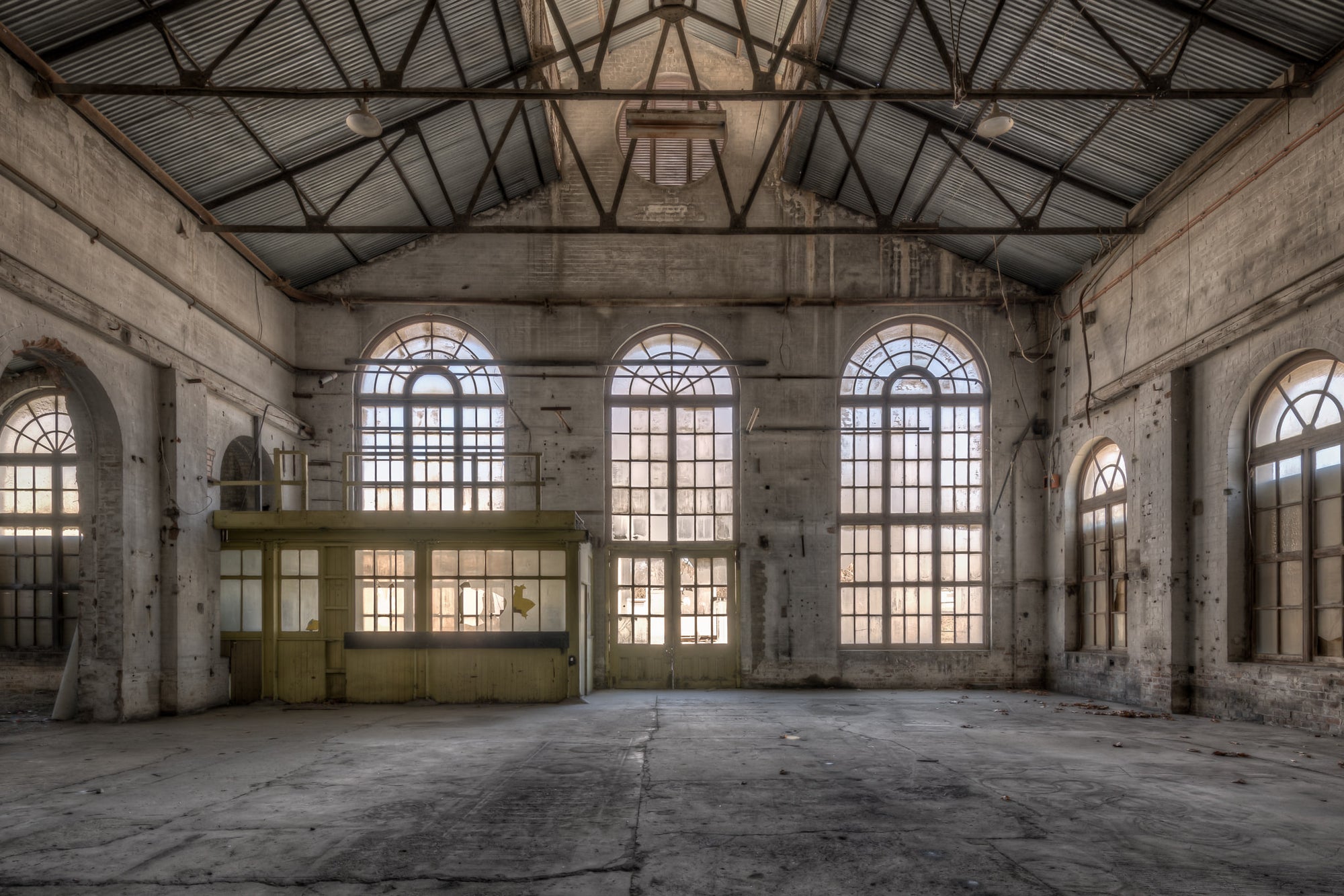 Power House Southern Interior at Portland Cement Works, light floods through five arched windows set into a concrete wall.