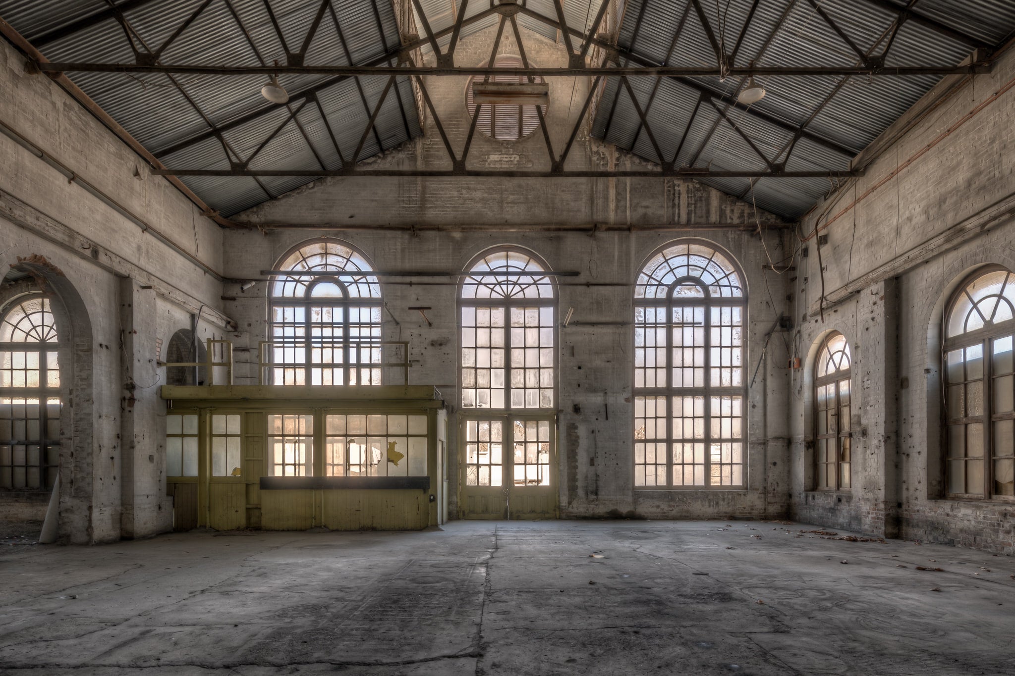 Power House Southern Interior at Portland Cement Works, light floods through five arched windows set into a concrete wall.