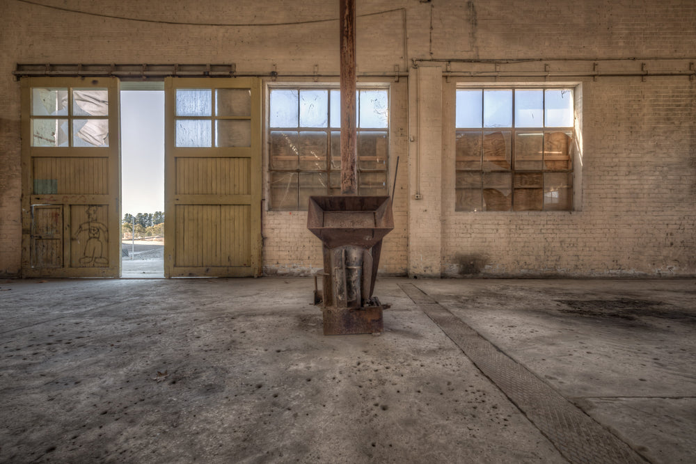 Stove Heater at Portland Cement Works, a cast-iron stove sits alone at the centre of a wide concrete floor.