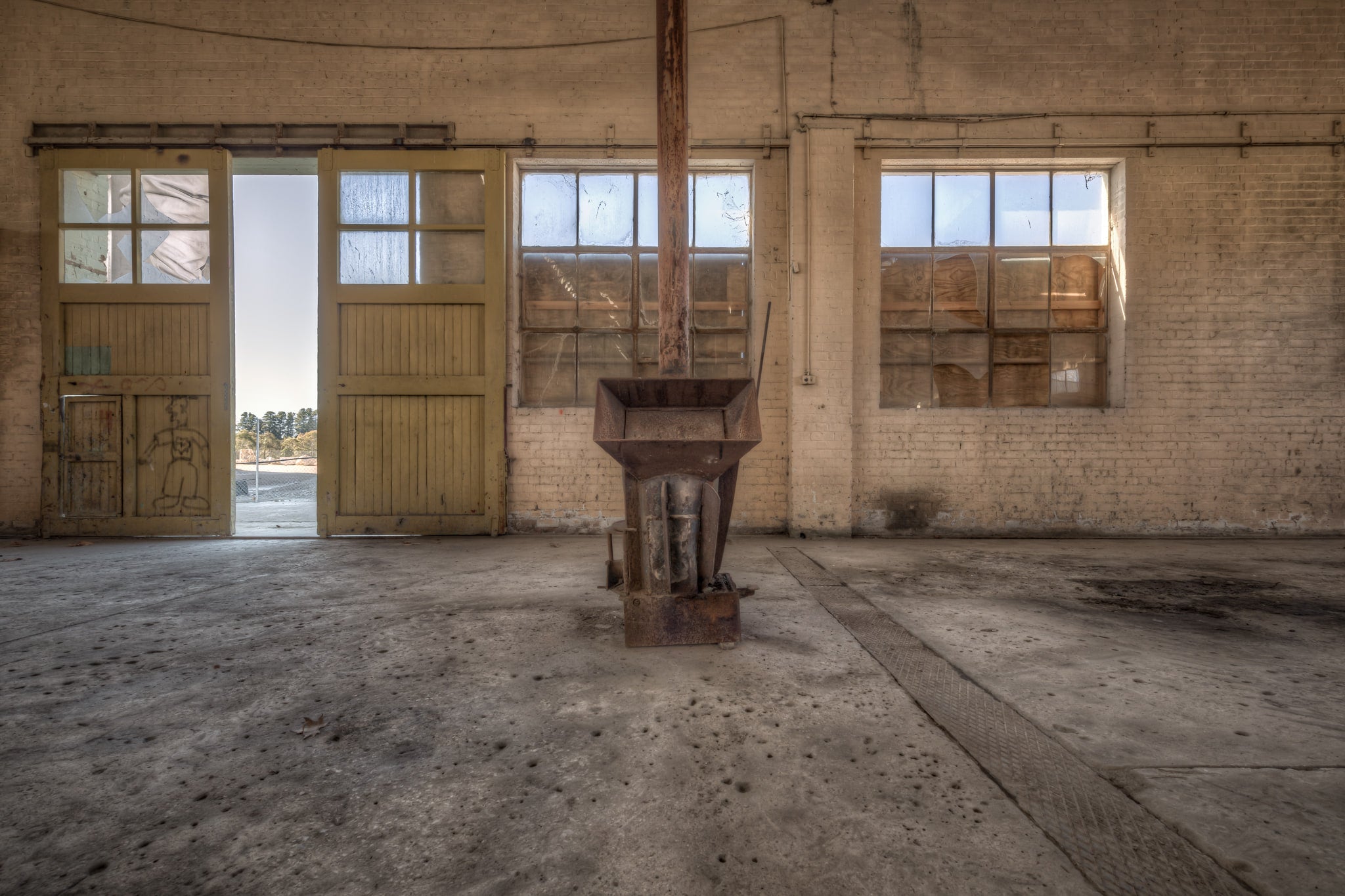 Stove Heater at Portland Cement Works, a cast-iron stove sits alone at the centre of a wide concrete floor.