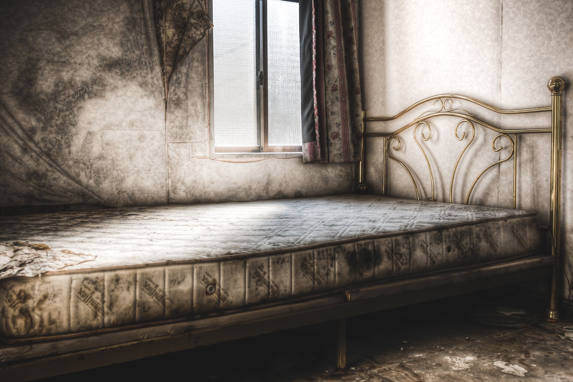 Bed at Seika Dormitory, a stripped bed frame rests within a decaying room at Seika Dormitory.